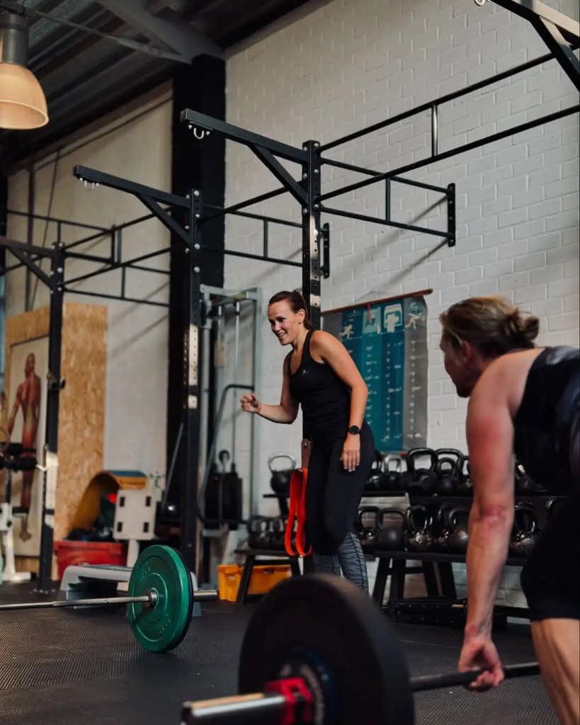 Deelnemers die in De Loods samen krachttraining doen met halters en materiaal