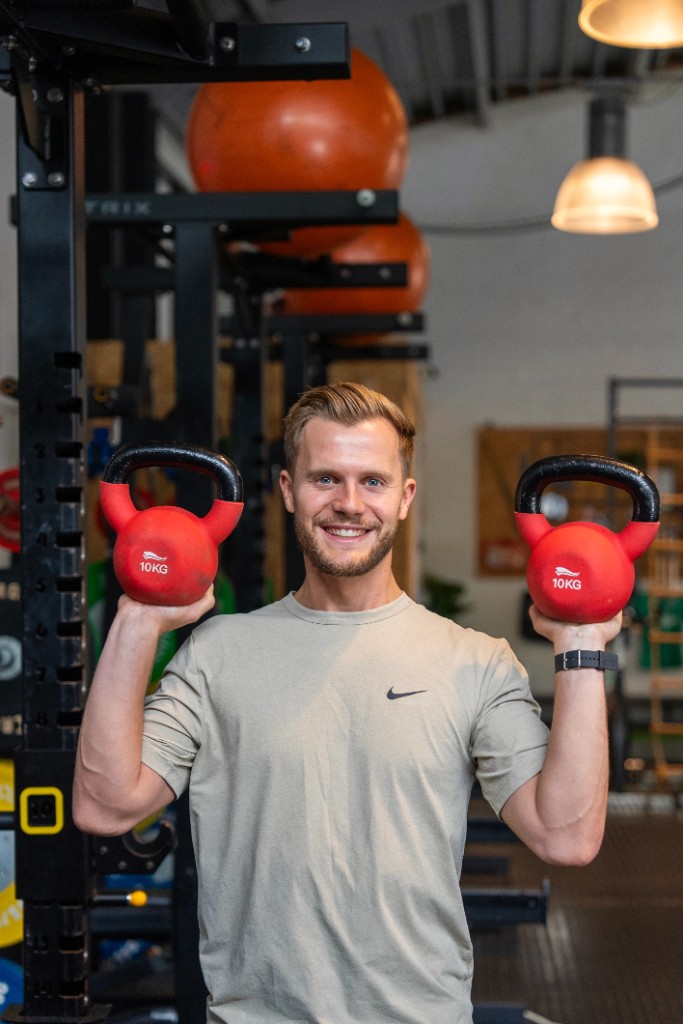 Trainer in de loods met twee rode kettlebells.
